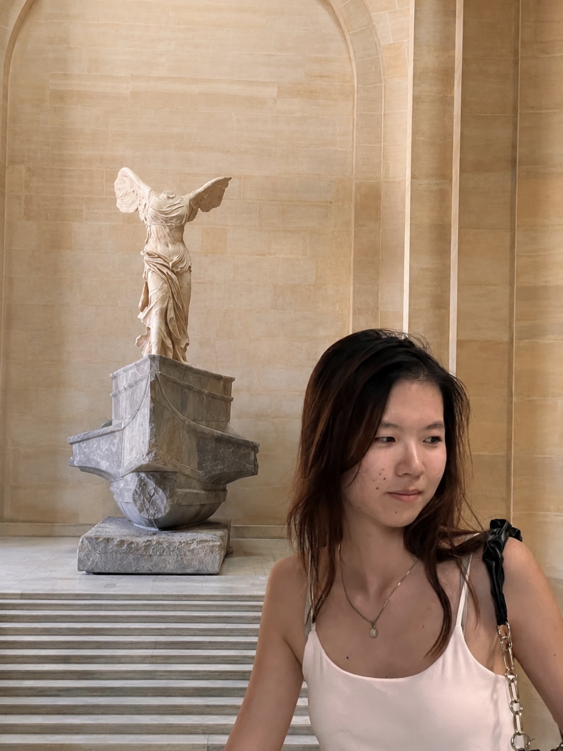 Fay Ouyang at the Louvre, with the Winged Victory of Samothrace behind her